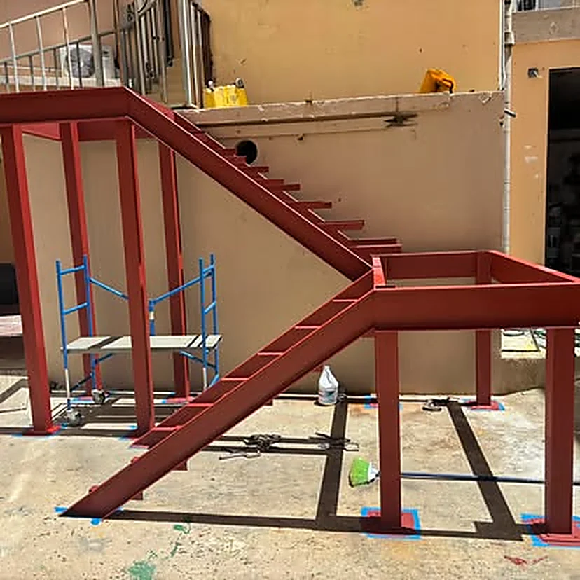 Escalera estructural y plataforma de acero fabricadas e instaladas por M&E, terminadas en pintura anticorrosiva