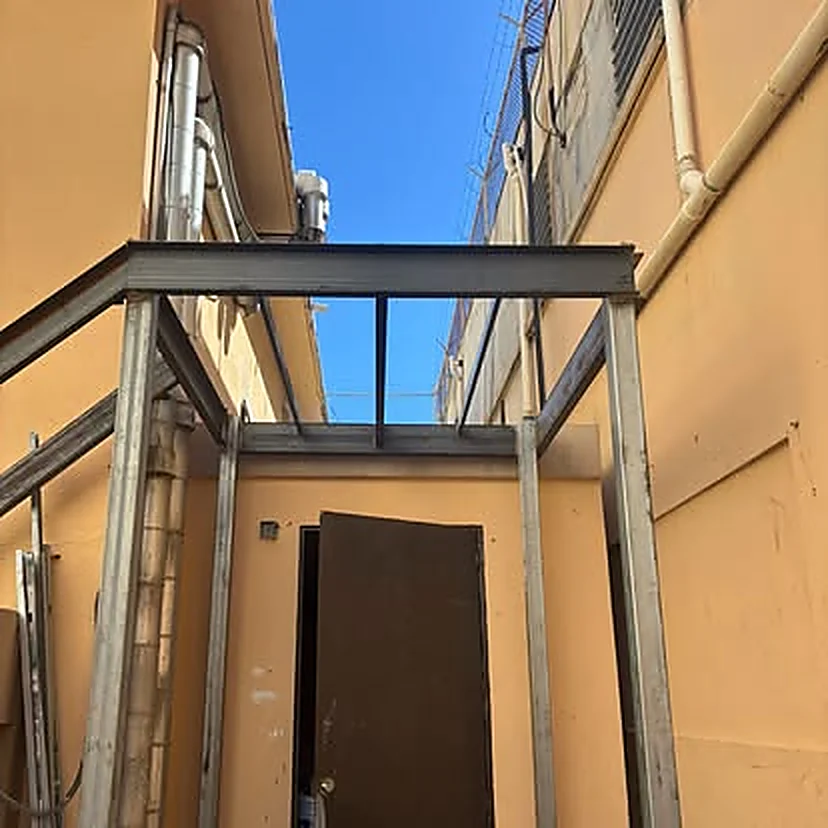 Estructura metálica de techo montada sobre un pasillo exterior